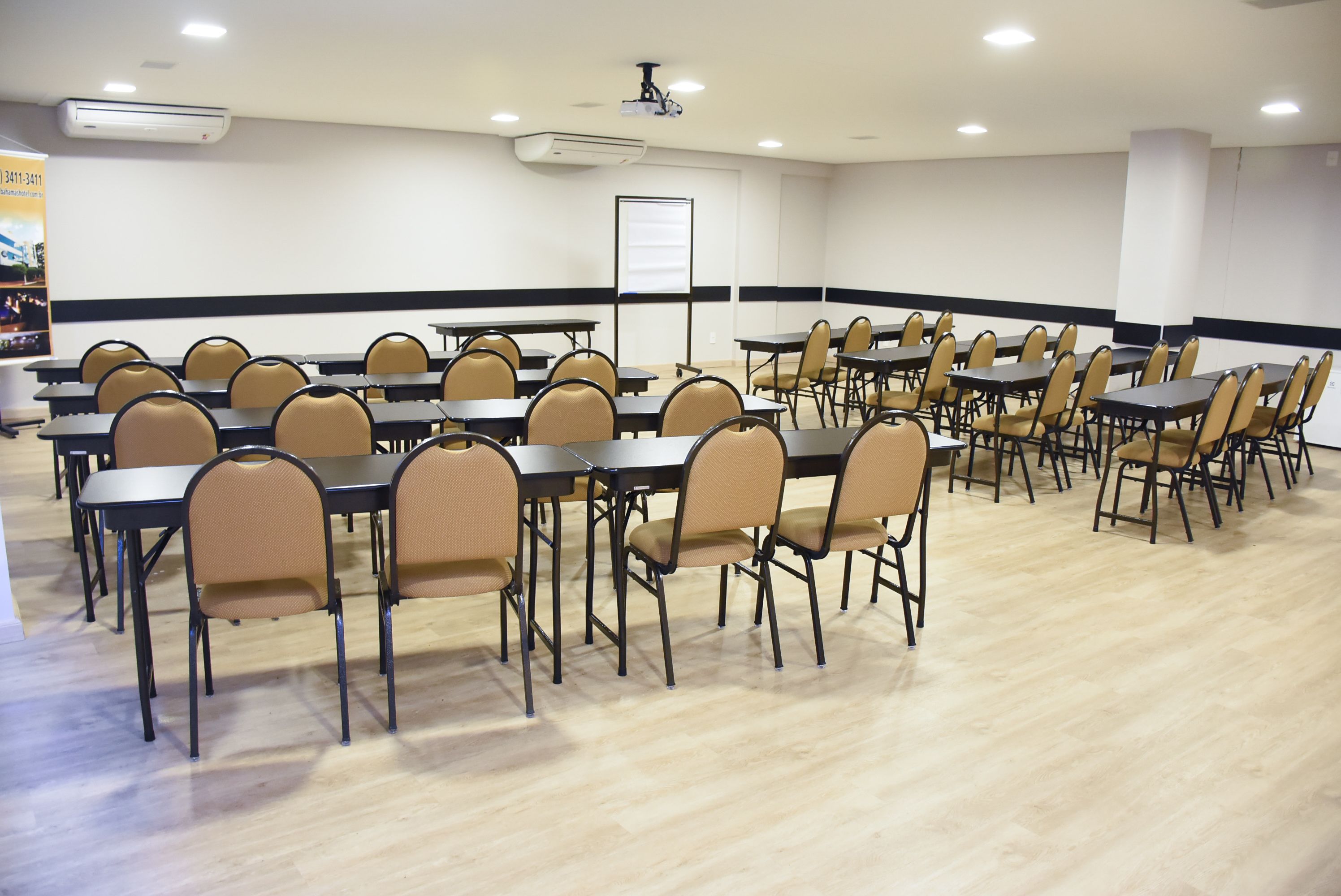 A conference room with multiple tables and chairs, air conditioning units, and a whiteboard.