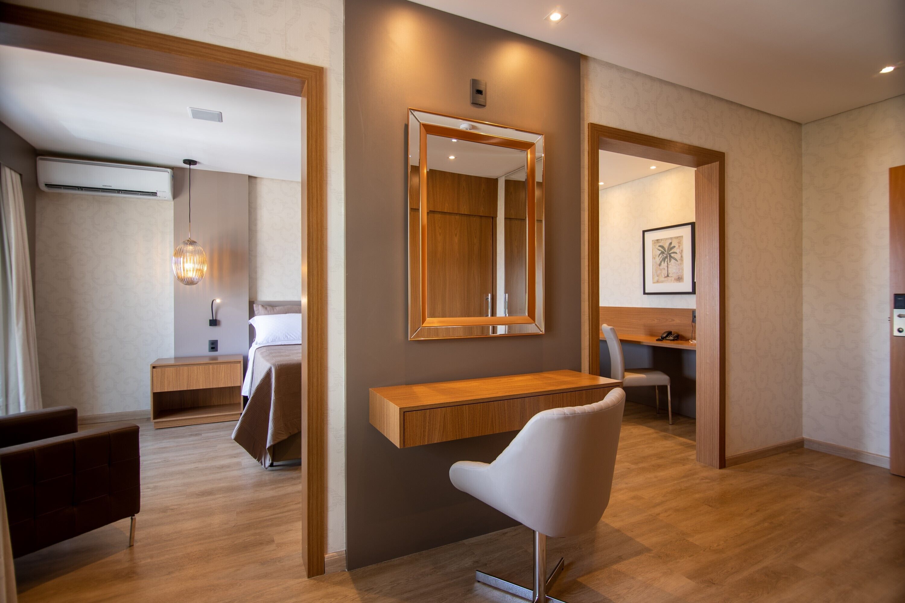 Une chambre d’hôtel moderne avec un bureau en bois, une chaise blanche, un grand miroir et un lit.