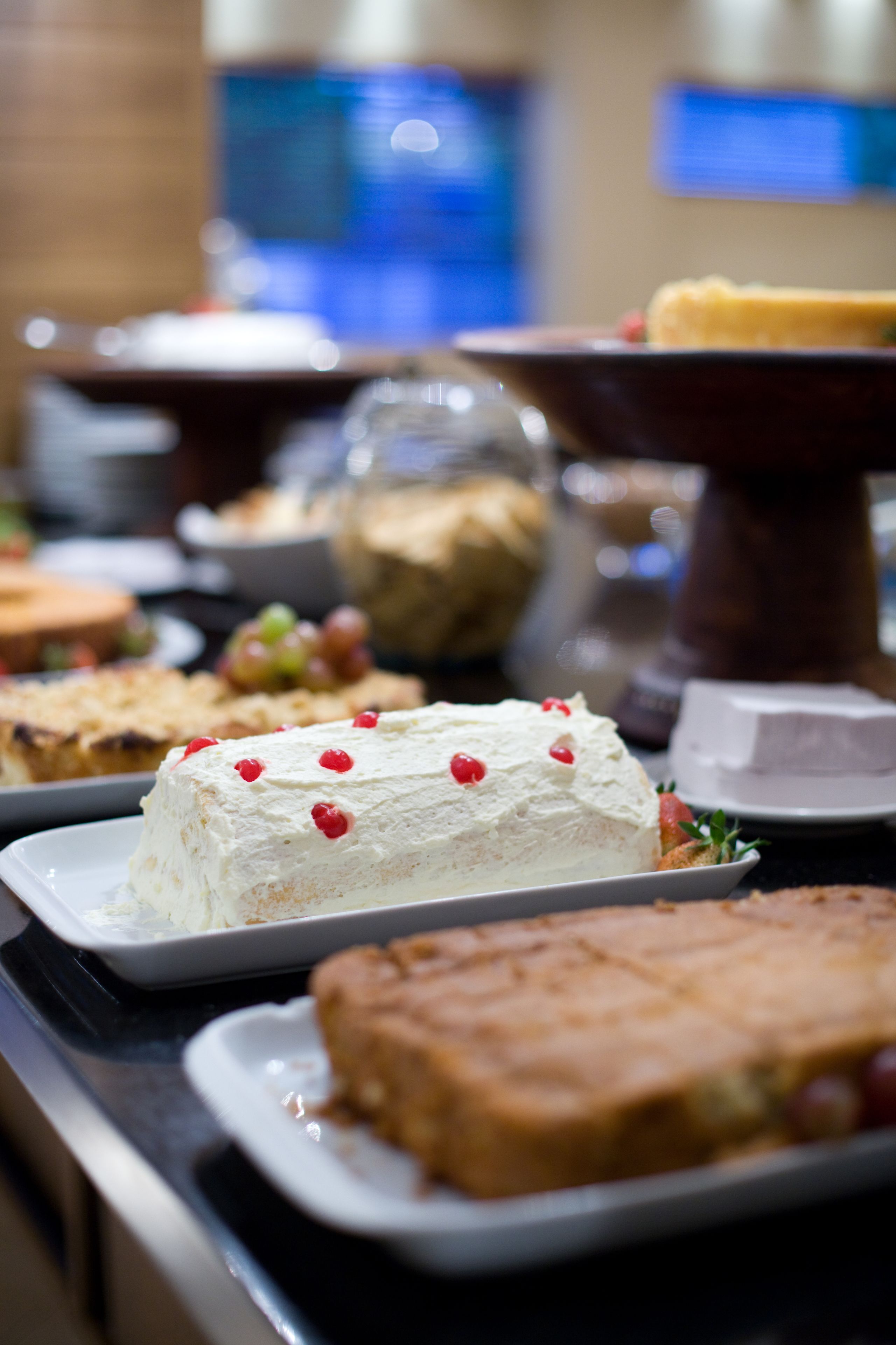 A buffet with various desserts including a cake with red berries and a cheesecake.