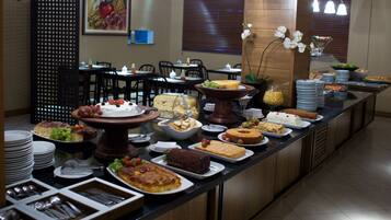 A buffet setup with various food items and a seating area with tables and chairs.