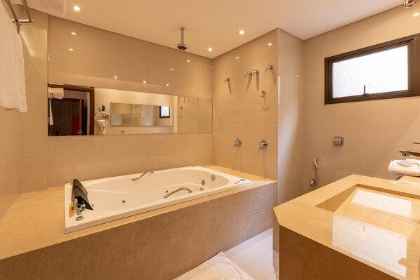 A modern bathroom with a large bathtub, a separate sink area, and a large mirror. - Hotel Bahamas (Dourados)