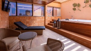 A modern outdoor relaxation area with a wooden ceiling, large windows, a built-in hot tub, wicker furniture, and a stone wall. - Hotel Bahamas (Dourados)