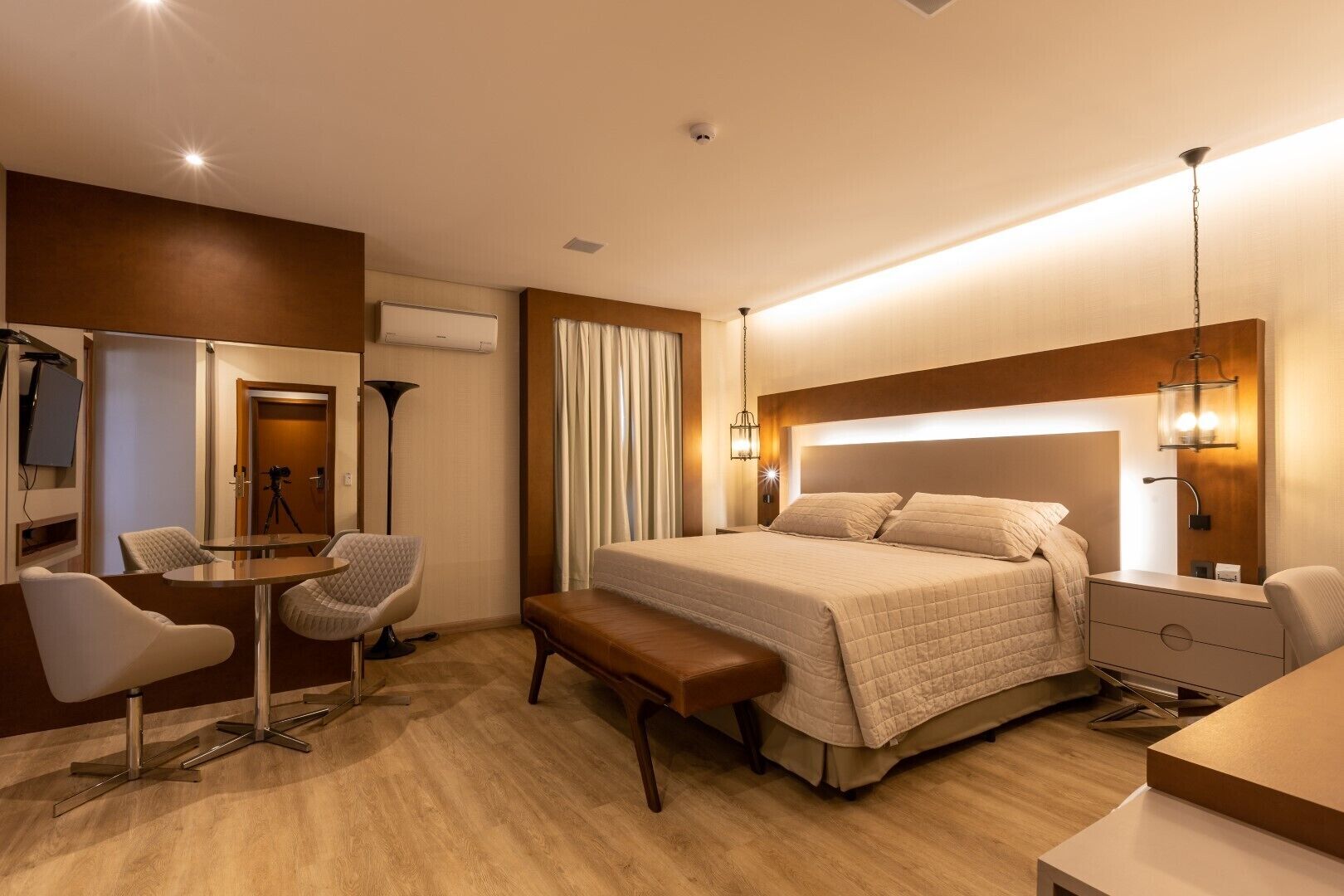 Una habitación de hotel moderna con una cama grande, un escritorio, una silla y un banco.