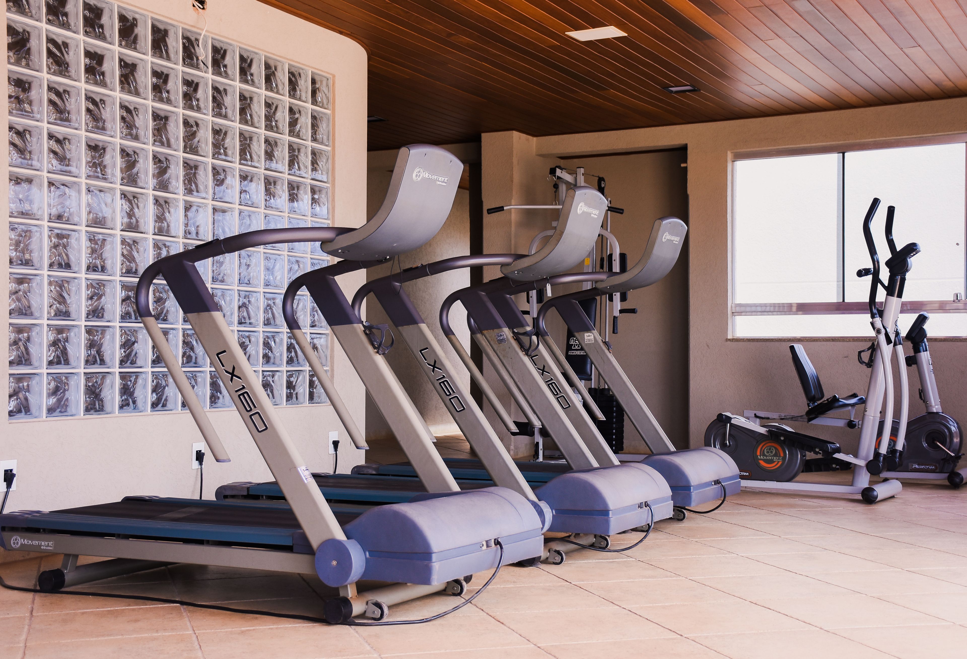 Un gimnasio con cintas de correr, bicicletas estáticas y una pared de fotos enmarcadas.