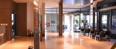 A modern hotel lobby with a polished marble floor, glass walls, and a reception desk.