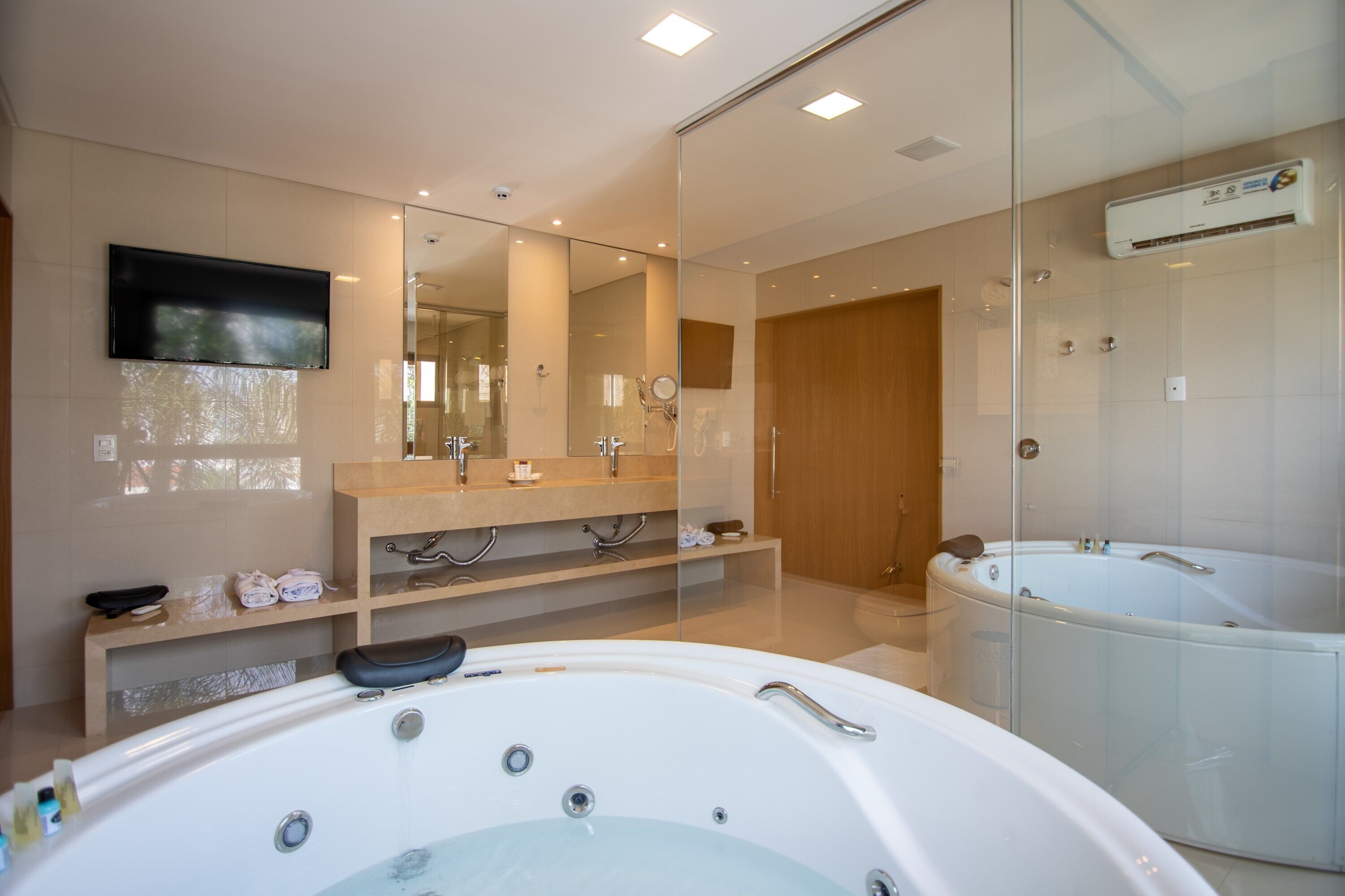 Un baño moderno con una bañera grande, una ducha con cerramiento de vidrio y un tocador con espejo.