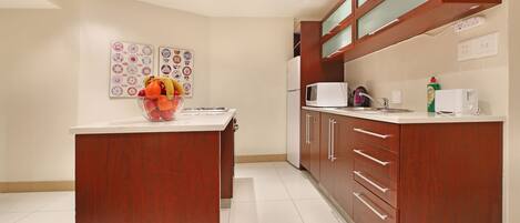 Una cocina moderna con armarios de madera, encimera blanca y un frutero.