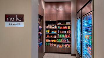 A grocery store aisle with shelves stocked with various food items and a refrigerated beverage display.