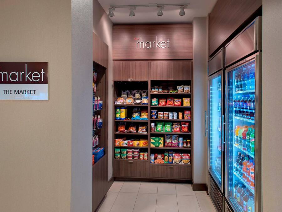 A grocery store aisle with shelves stocked with various food items and a refrigerated beverage display.