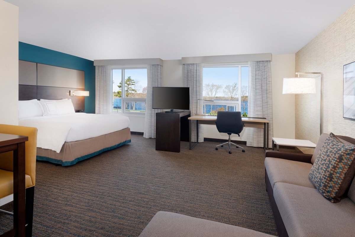 A hotel room with a bed, desk, chair, and a sofa.