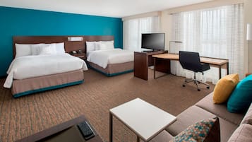 Habitación de hotel con dos camas, un escritorio, un televisor y un sofá.