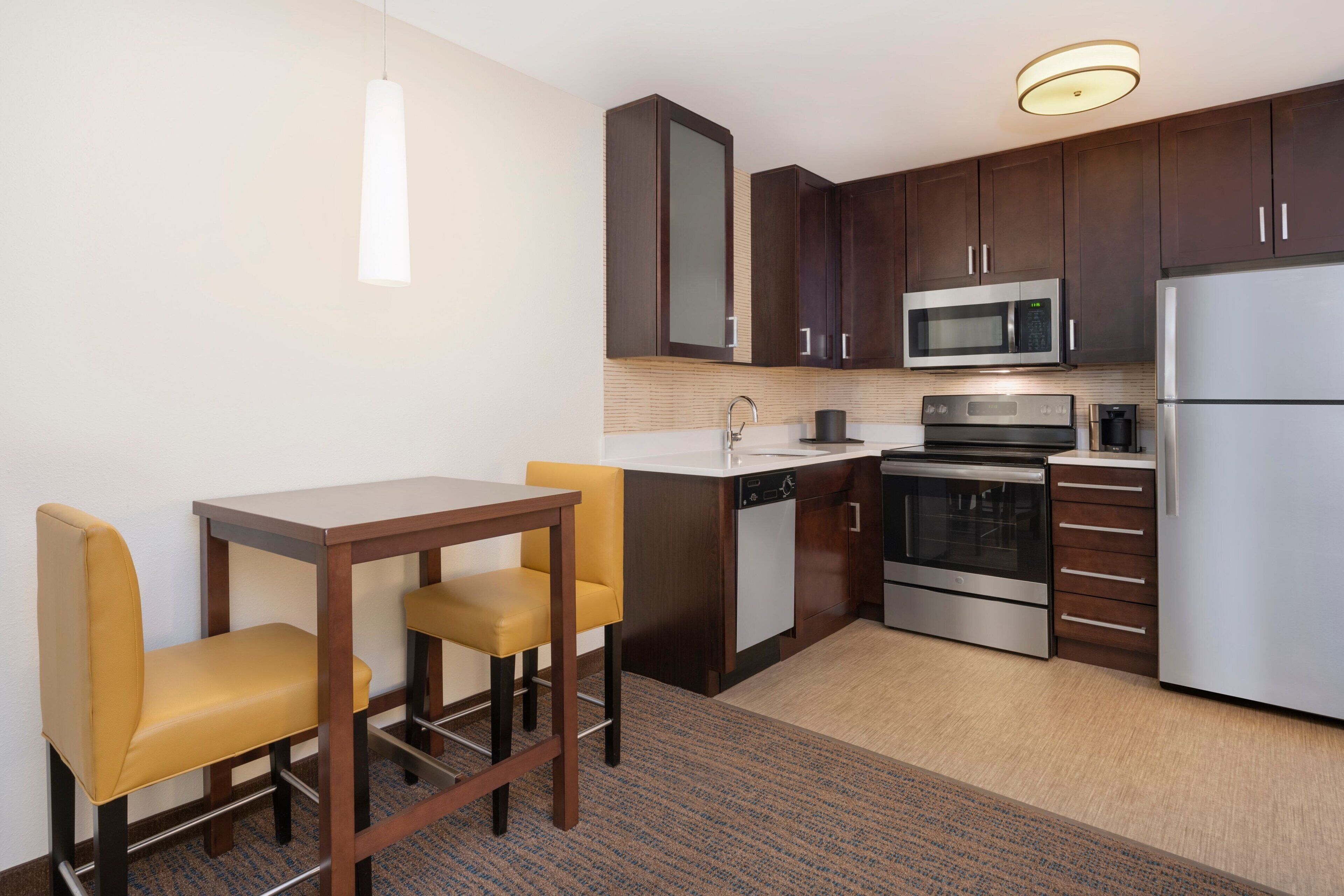 Una cocina compacta con comedor, que incluye microondas, horno y refrigerador.