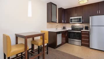 Una cocina compacta con comedor, que incluye microondas, horno y refrigerador.
