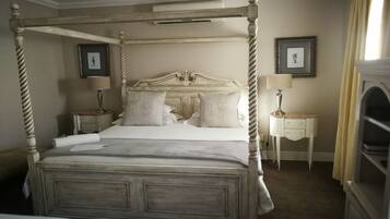 A four-poster bed with a wooden frame, two bedside tables with lamps, and a framed picture on the wall.