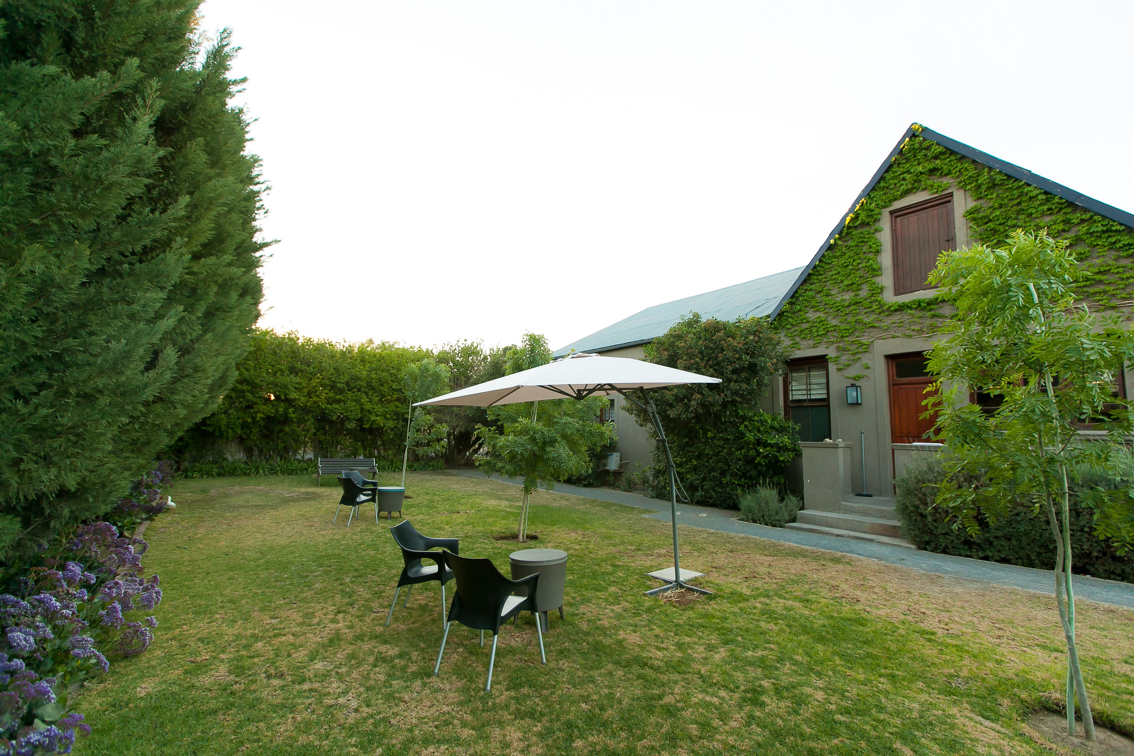 Un jardín bien cuidado con un patio amueblado y un gran paraguas.