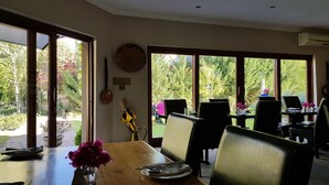 Un coin repas avec une table en bois, des chaises et une vue sur le jardin grâce à de grandes fenêtres.