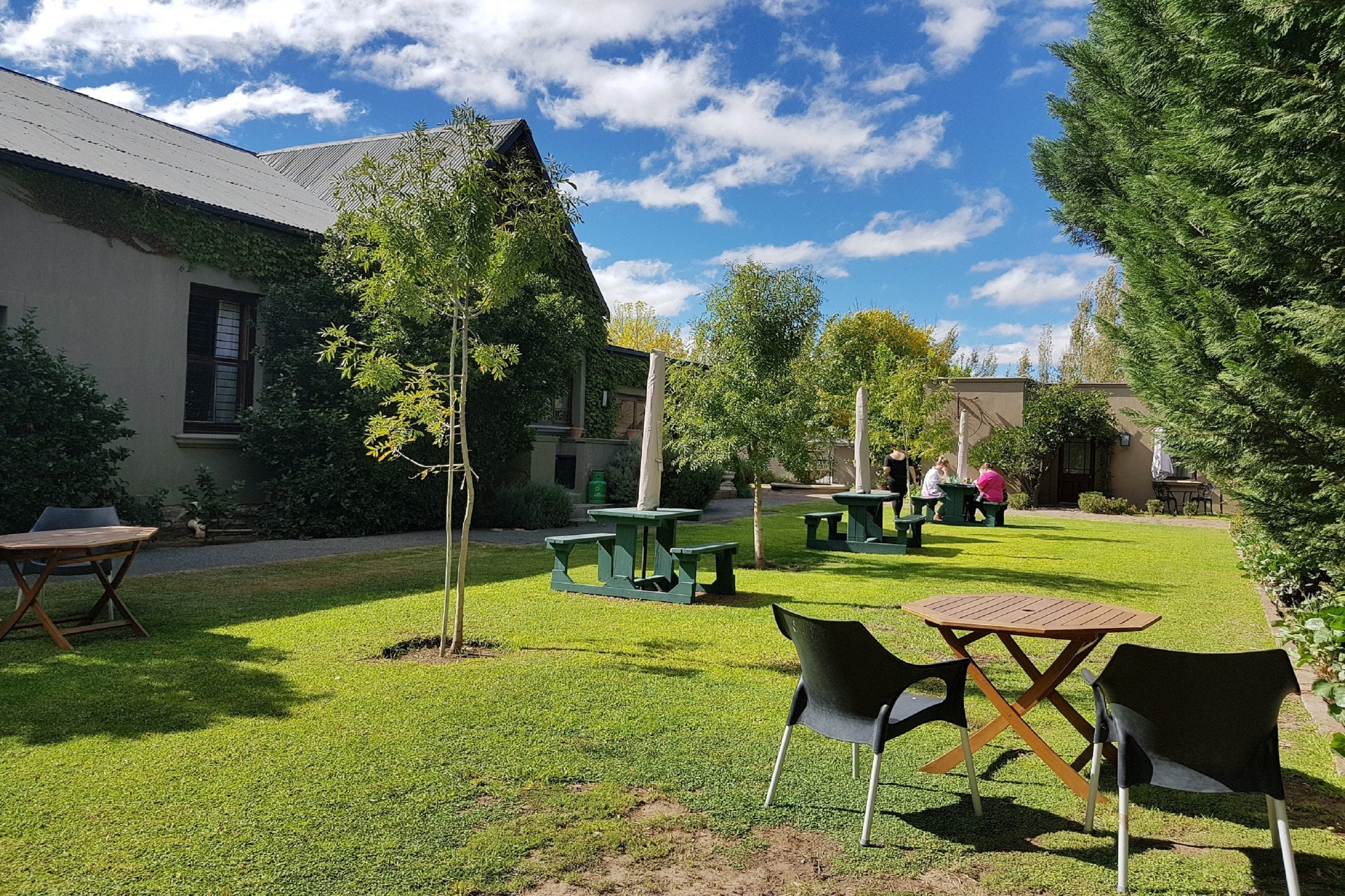 A courtyard with green grass, outdoor seating, and a building with a sloped roof.