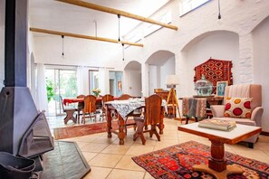A spacious living area with a fireplace, dining table, and comfortable seating. - Waters on Willows (Pretoria)