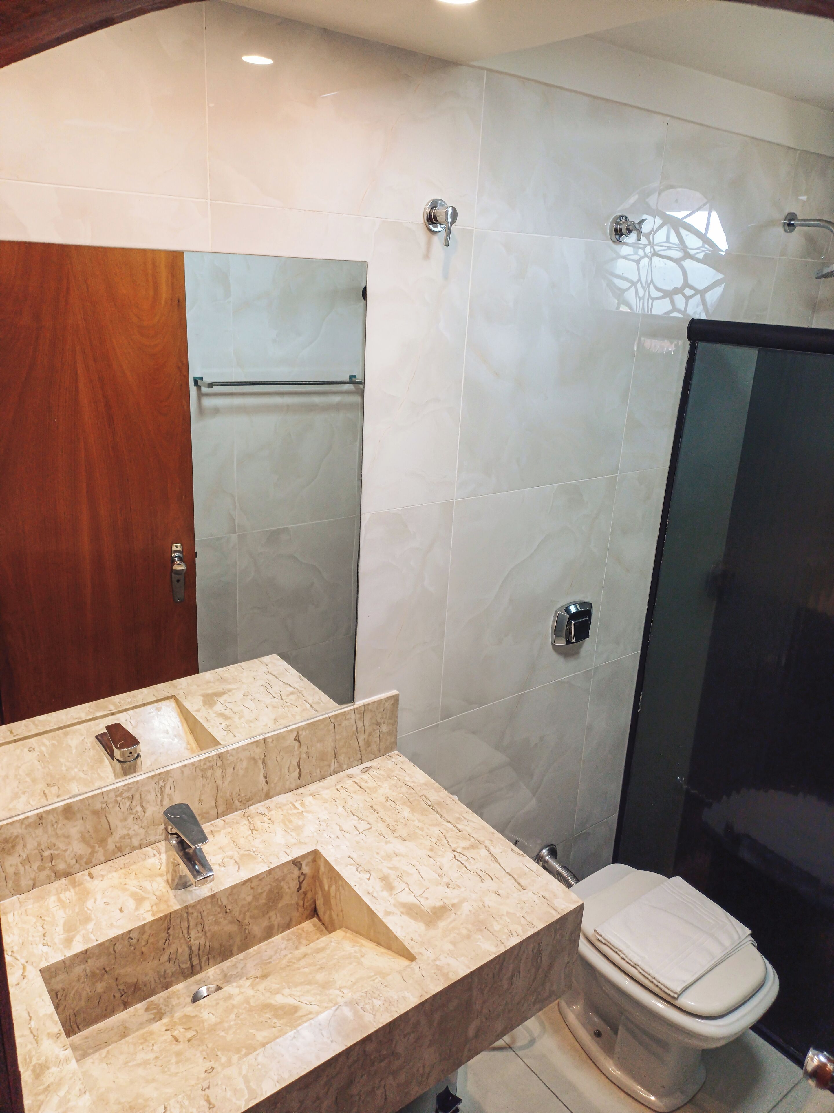A bathroom with a marble sink, a toilet, and a glass shower enclosure.