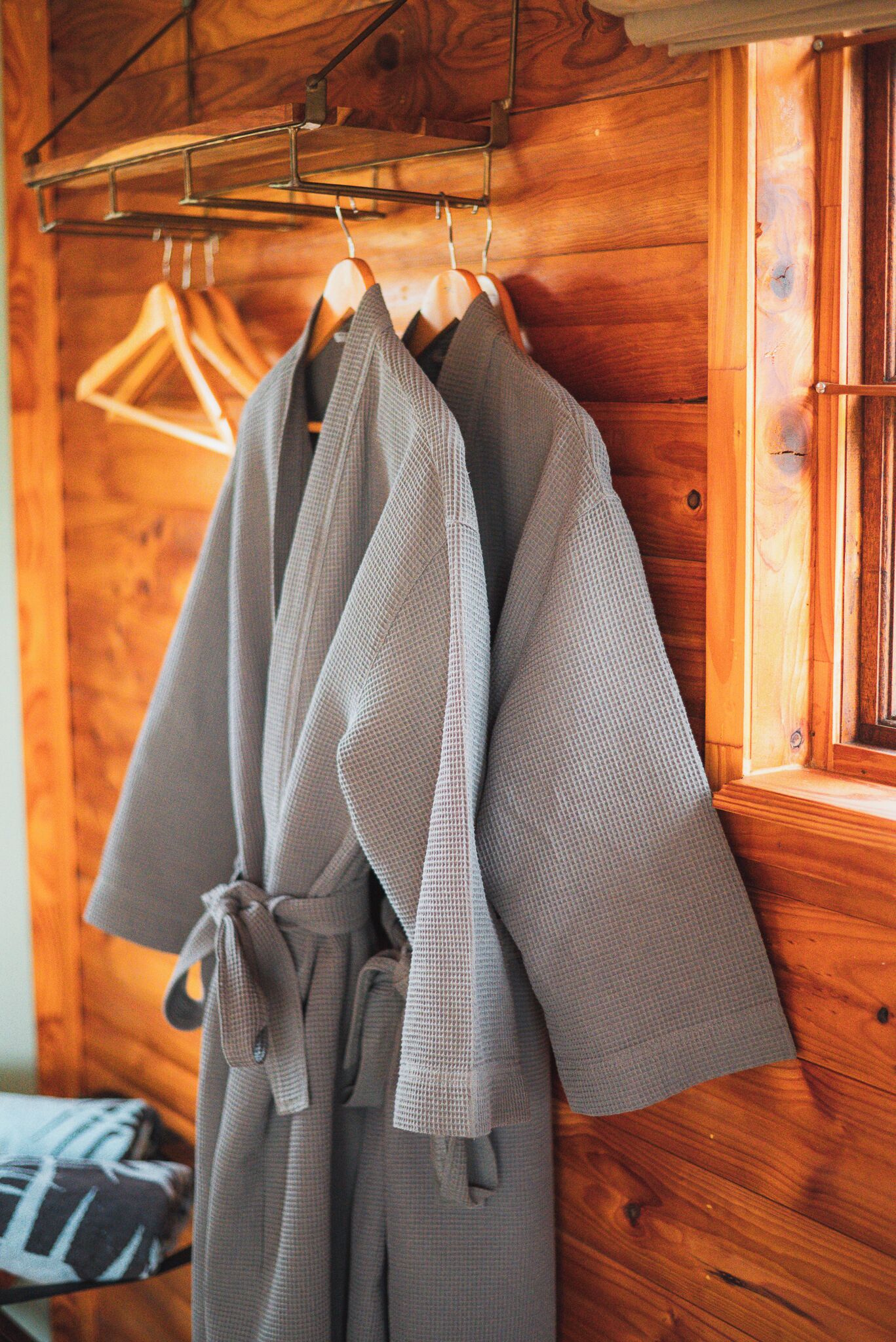 A wooden wall with a metal rack holding a grey robe.