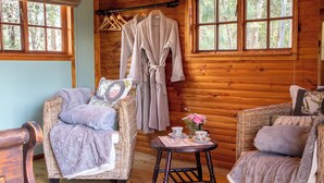 L’intérieur chaleureux d’un chalet avec des meubles en osier, un mur en bois et une fenêtre donnant sur la forêt.