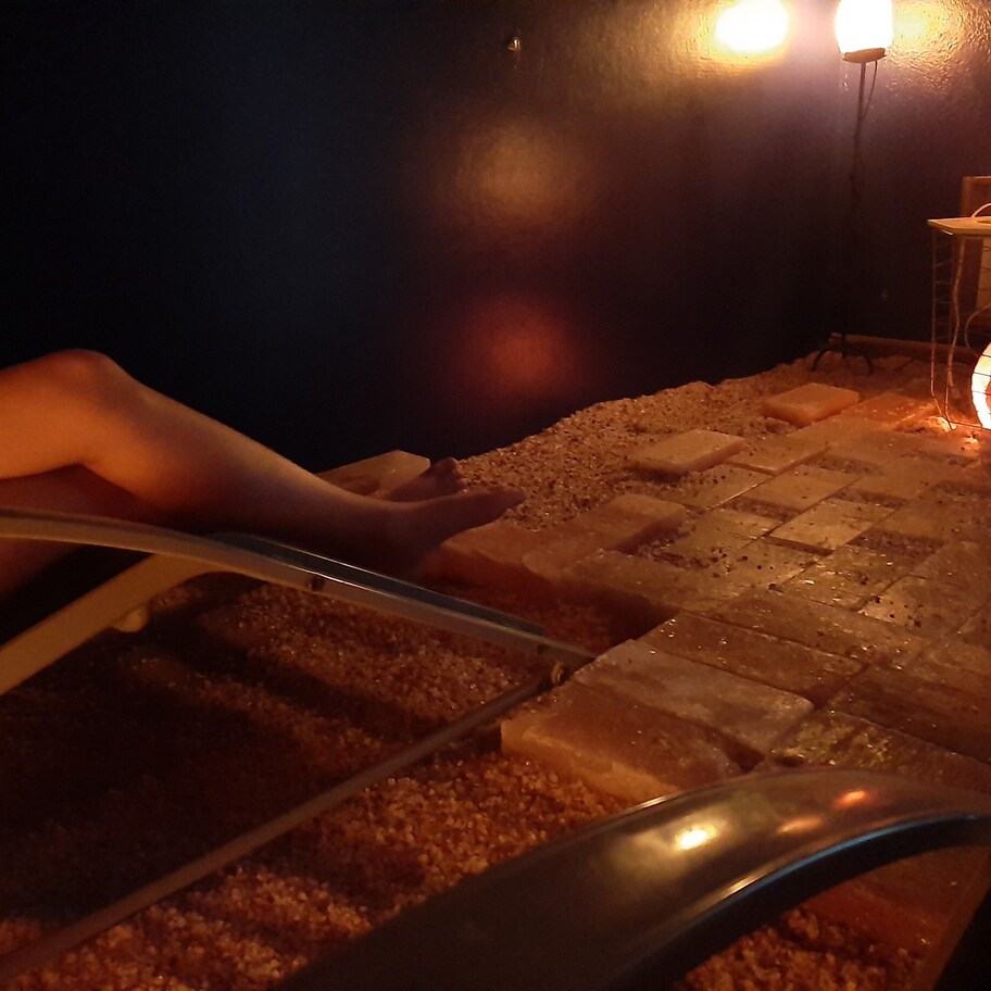A person sitting on a chair with a tray of food, a lit candle, and a small table with a candle in the background.