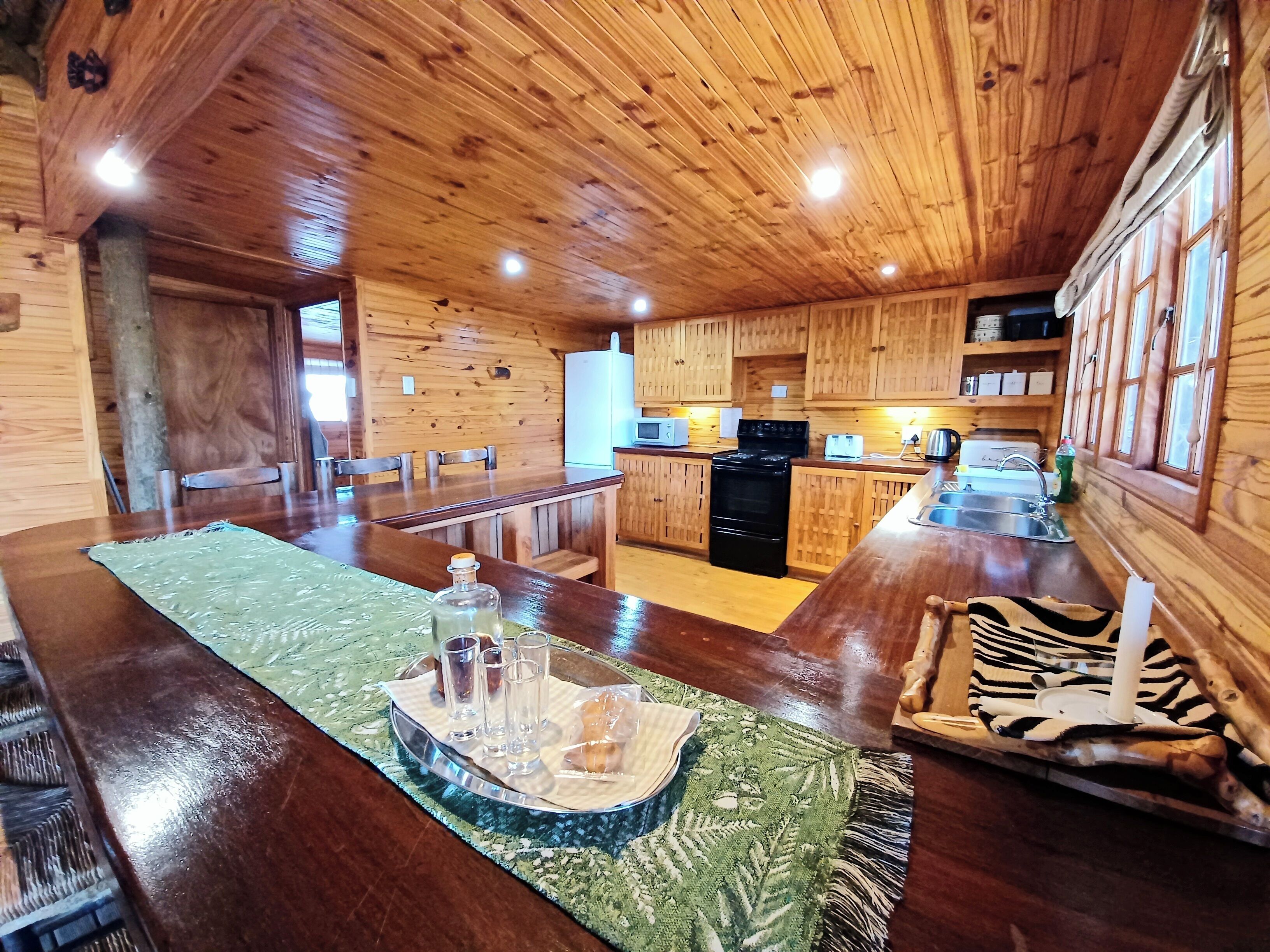 L’intérieur d’une cabane en bois comprend un coin repas, une cuisine et une grande fenêtre.