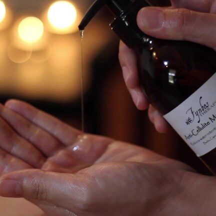 A hand holding a bottle of massage oil.