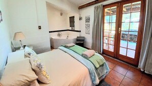 Une chambre avec un grand lit, une salle de bain avec une baignoire et une porte-fenêtre coulissante donnant sur l’extérieur.