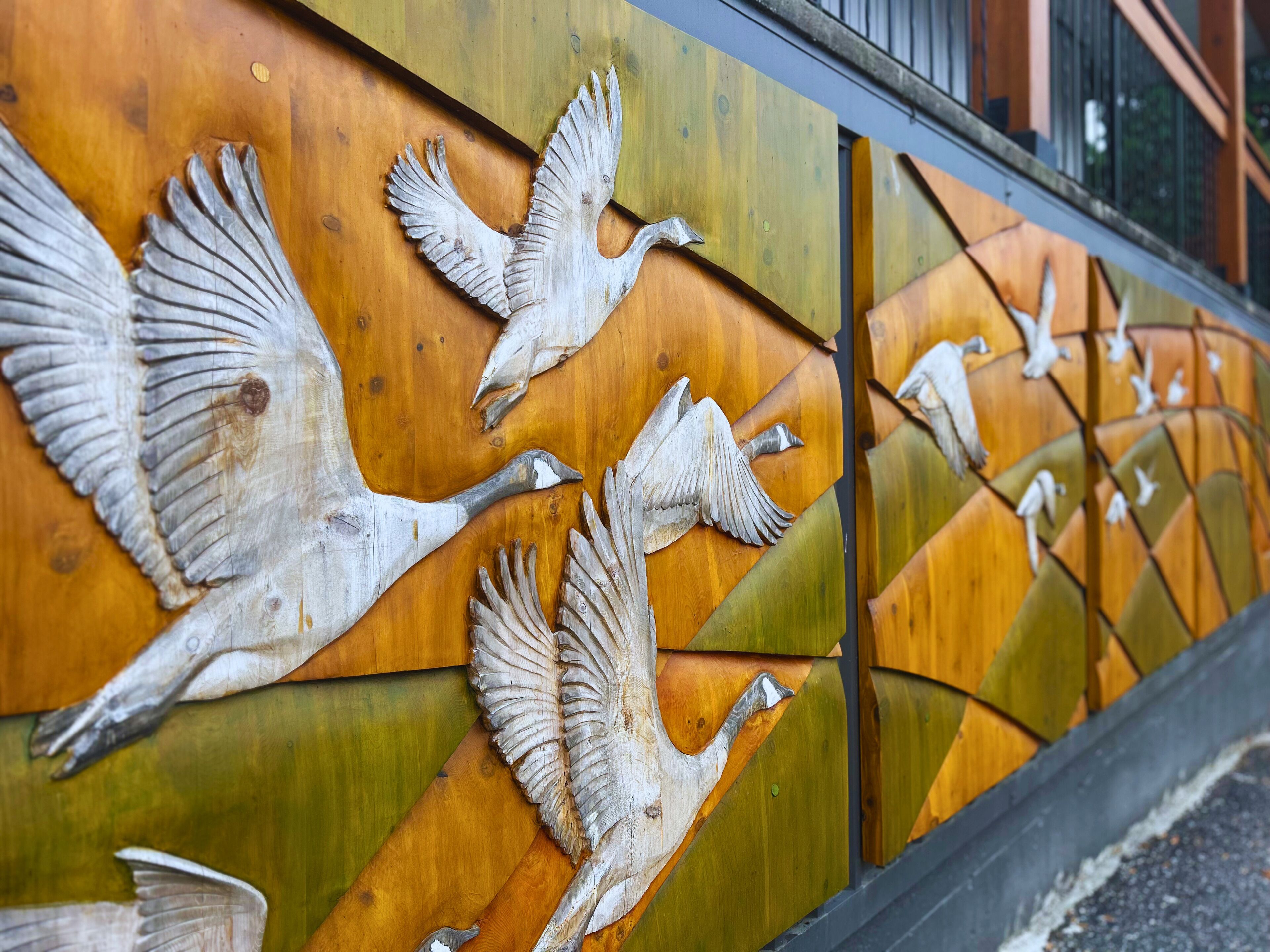 Pared con un panel de madera que presenta una escultura de un pájaro.