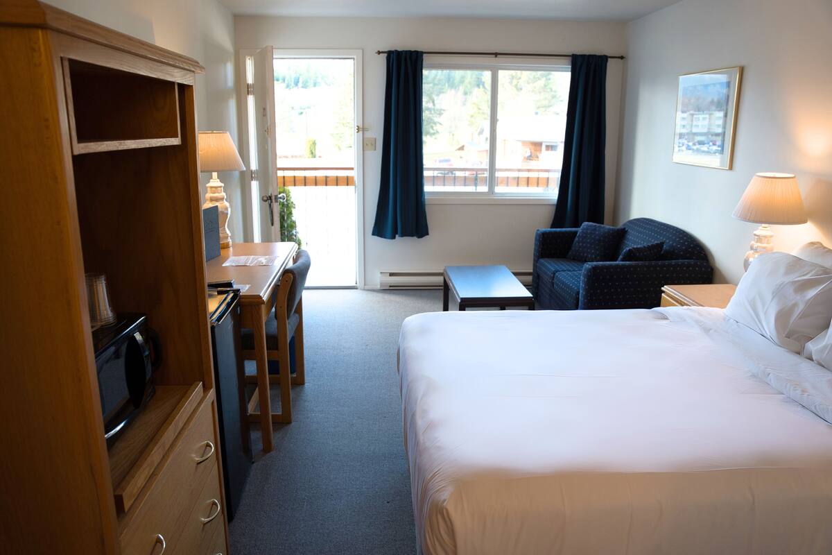 Una habitación de hotel con una cama, un escritorio, una silla y una pequeña mesa.