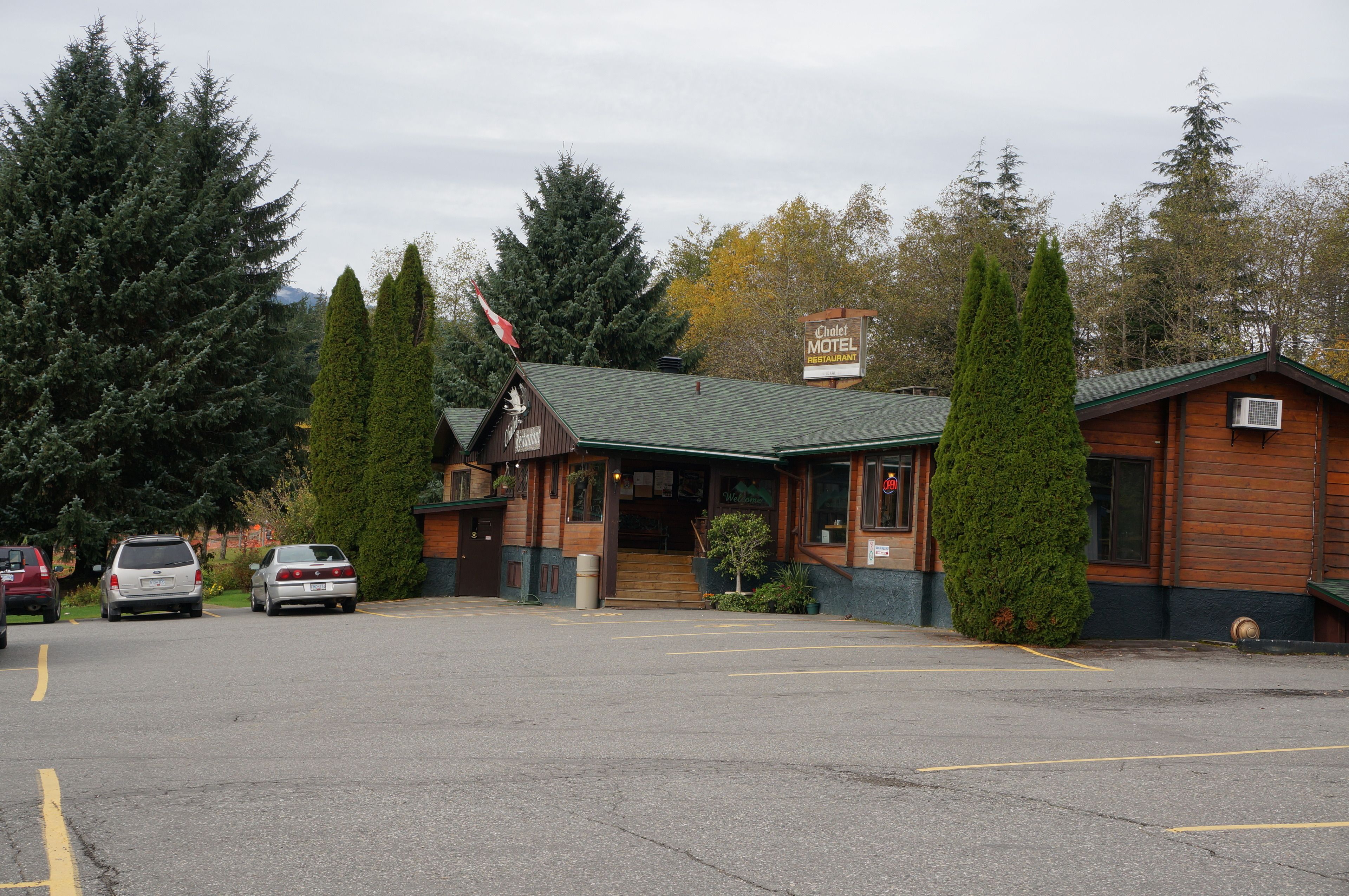 A motel with a green roof, wooden exterior, and a signboard.