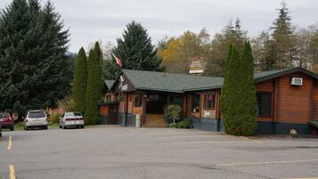 A motel with a green roof, wooden exterior, and a signboard.