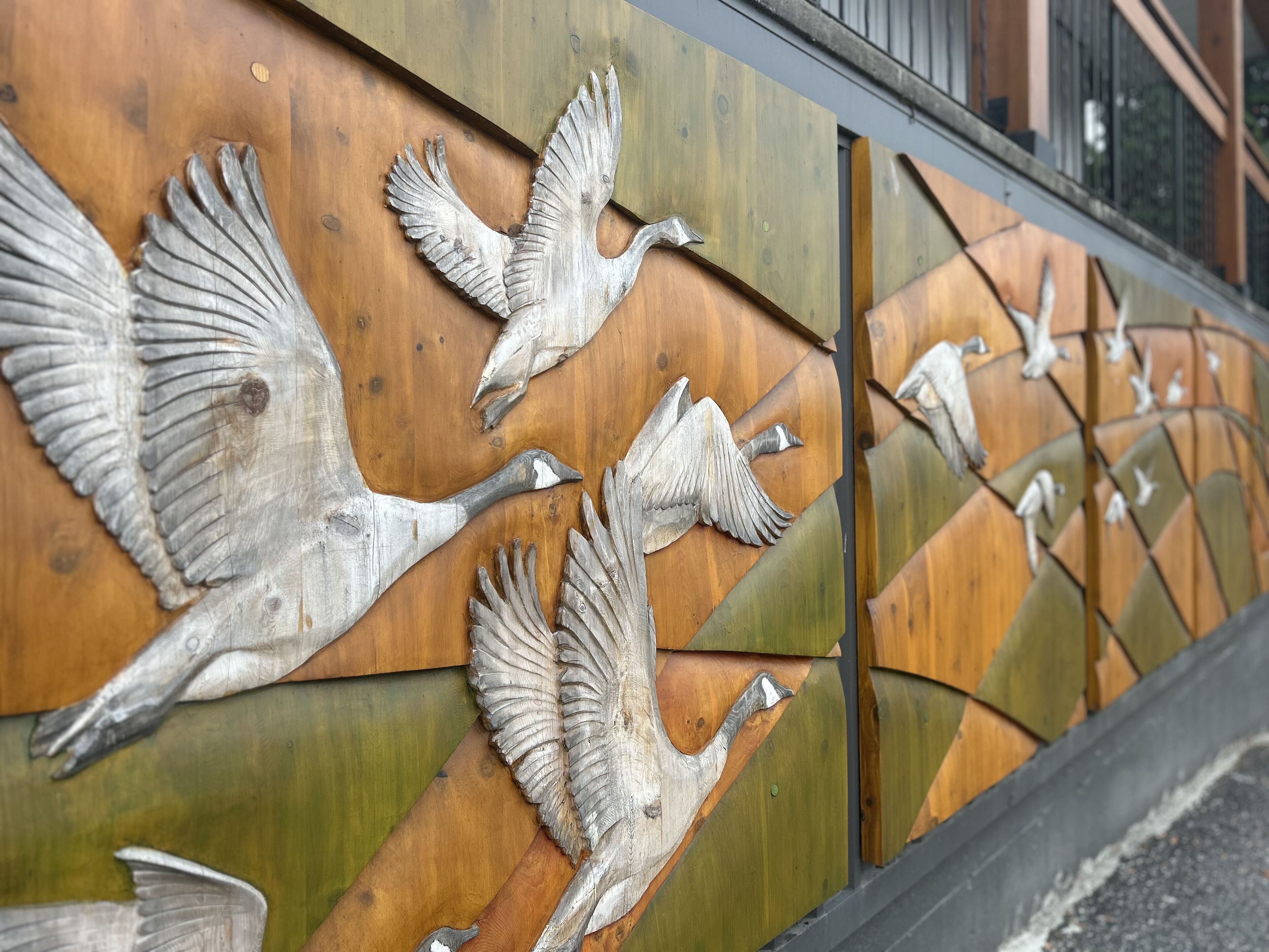 Una pared con varias esculturas de aves en pleno vuelo.