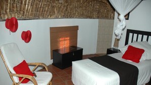 Una habitación con una cama, una silla, una mesita de noche y una pequeña mesa.