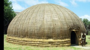Una estructura tradicional en forma de cúpula, con una entrada central, rodeada de césped.