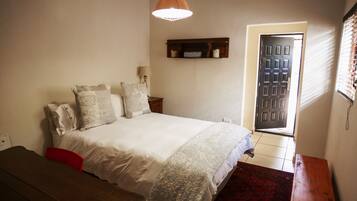 Un dormitorio con cama, mesita de noche, lámpara y una puerta con ventanal.