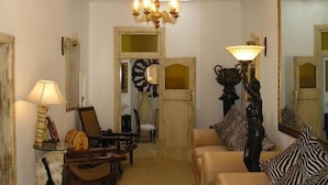A living room with a chandelier, a sofa, a chair, and a lamp. - Victorian Guest House (Krugersdorp)