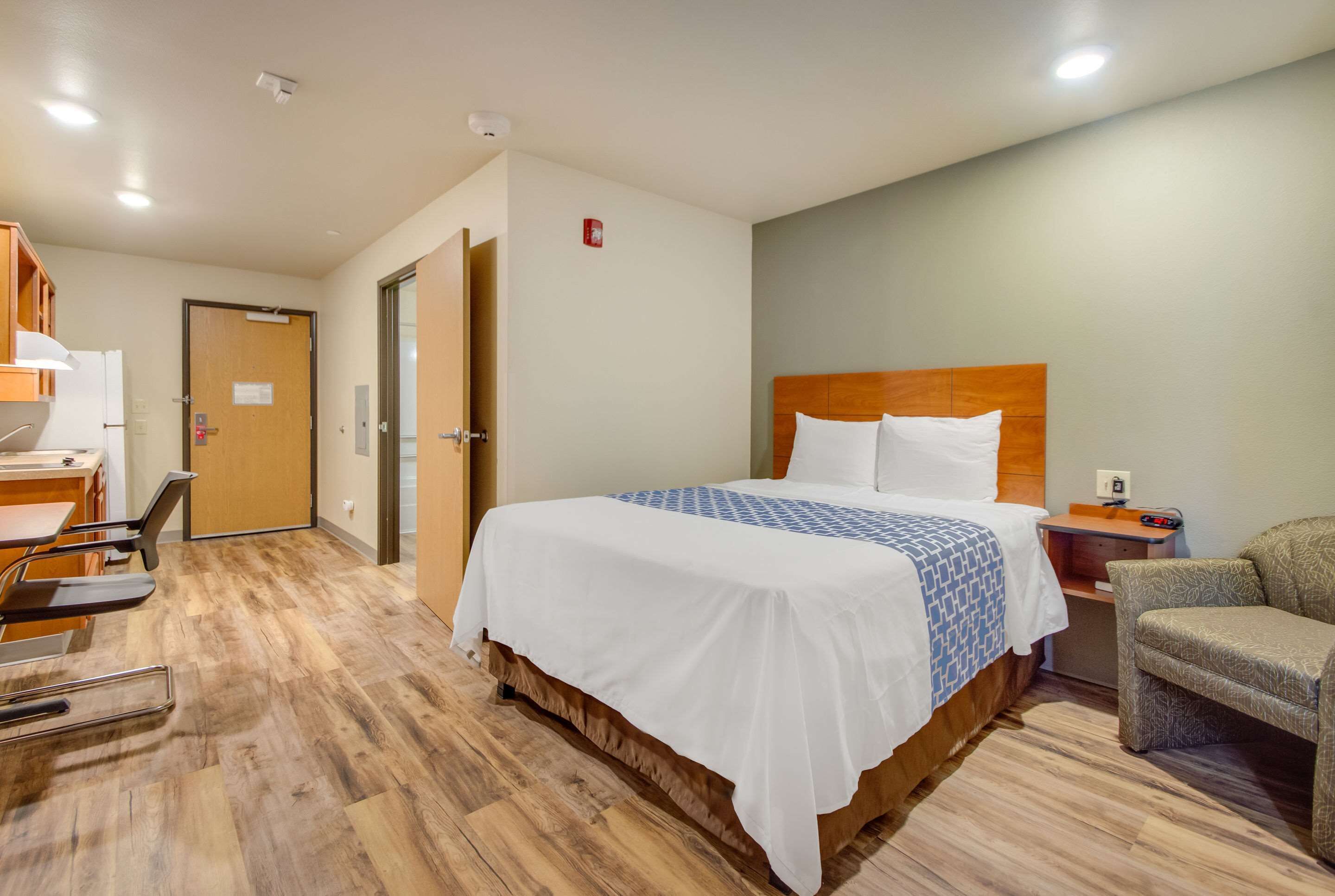 Una habitación de hotel con una cama, un escritorio y una silla.