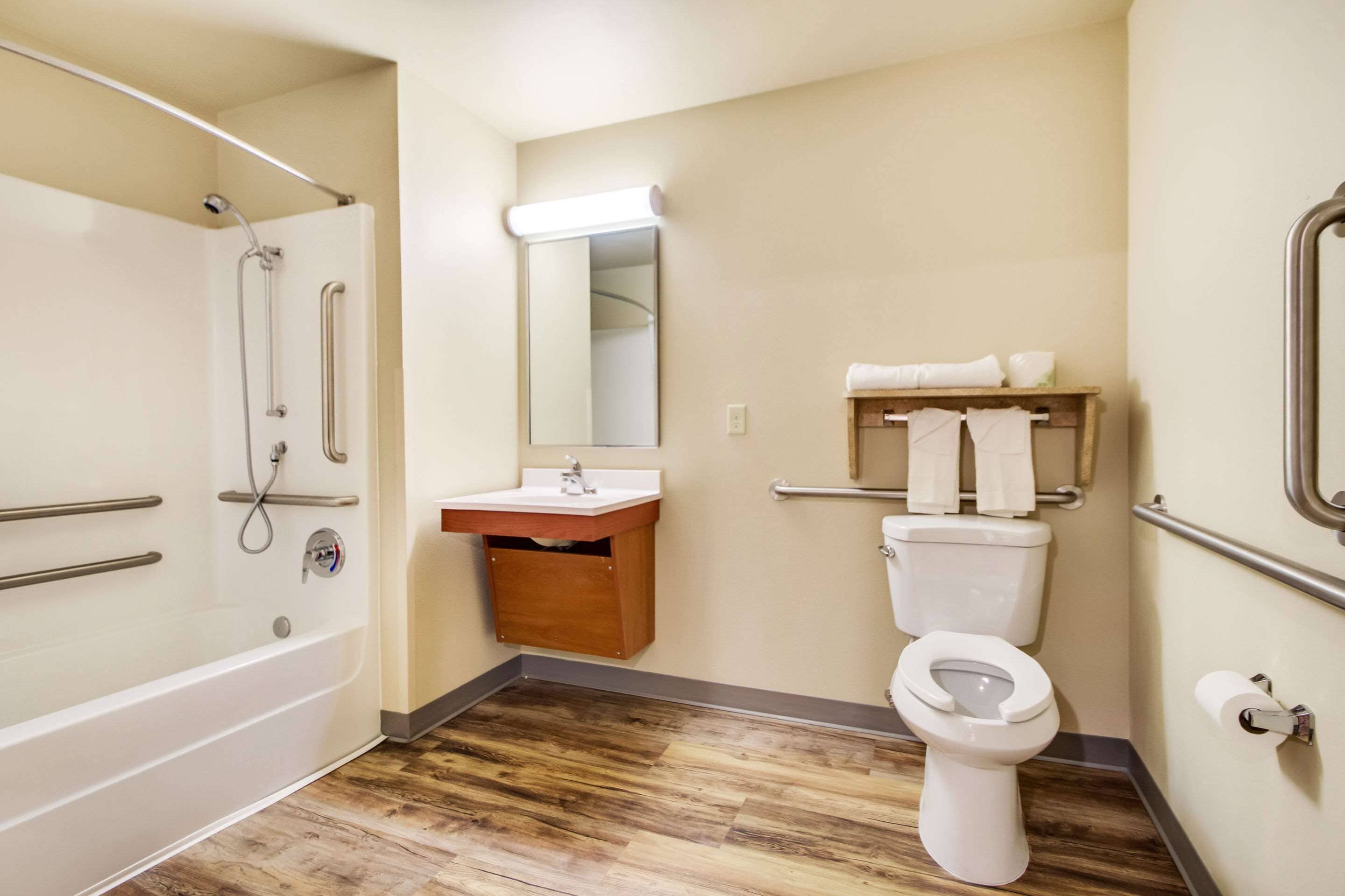 Un baño con bañera, lavabo, espejo, inodoro y suelo de madera.