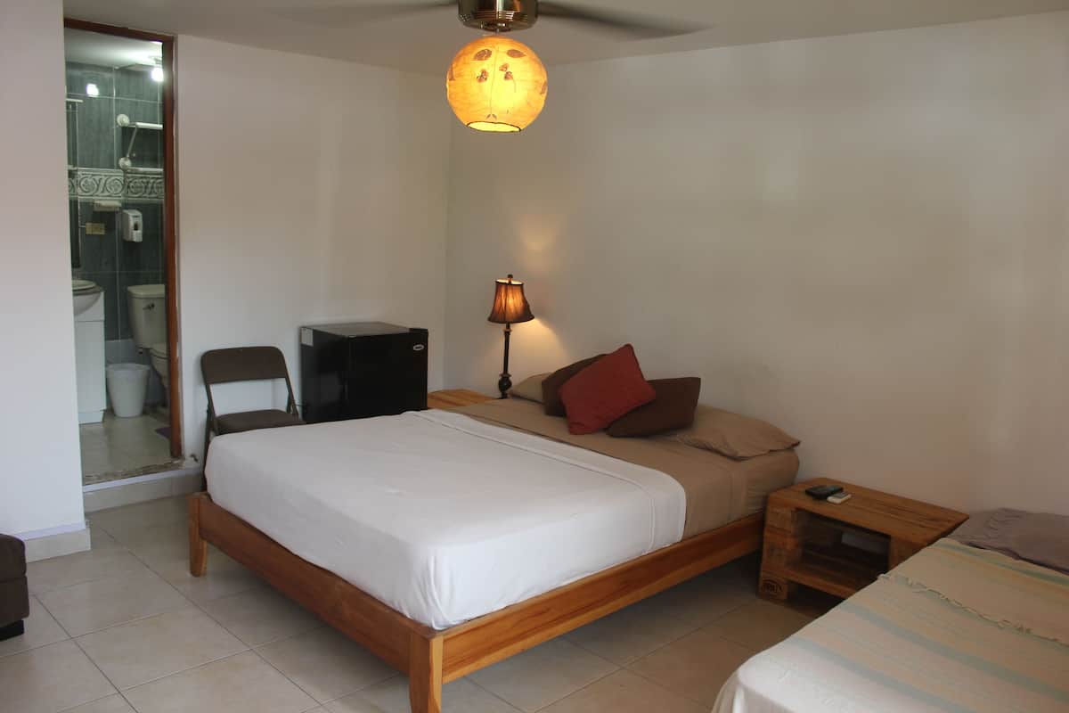 Un dormitorio con cama de madera, una mesita de noche, una lámpara y una pequeña mesa.