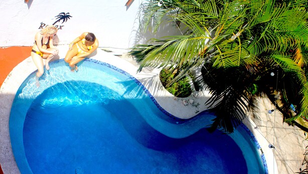 A swimming pool with two people sitting on the edge. - Hostel Casa Areka (Panama City)