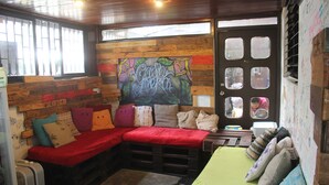 A cozy room with a wooden wall, a red sofa, a green sofa, and a wooden bench. - Hostel Casa Areka (Panama City)