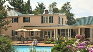 A two-story house with a swimming pool, outdoor furniture, and a covered patio area. - L'Auberge Provencale Inn & Restaurant (Boyce)