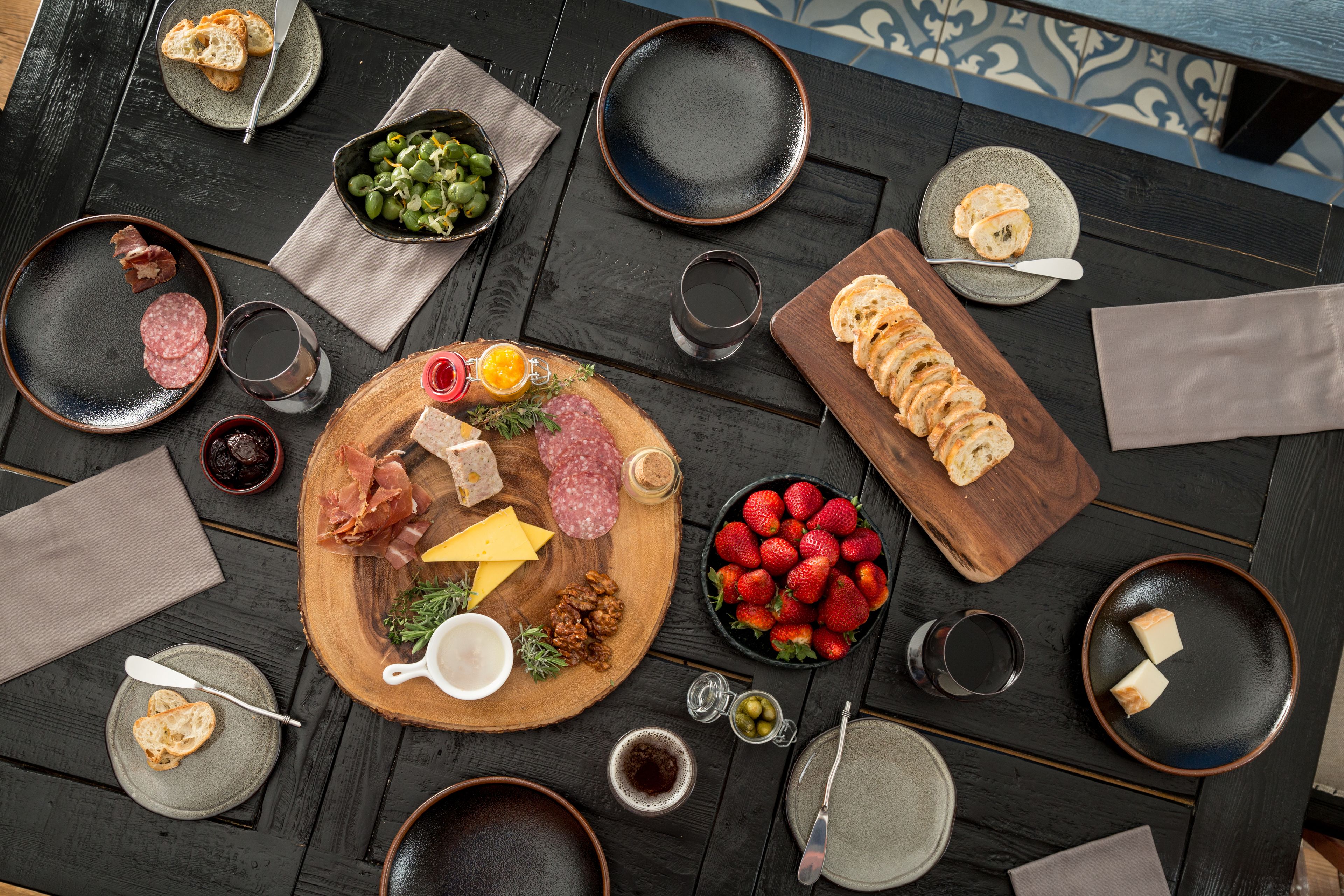 A table set with various food items, including cheese, meats, and bread, arranged on a wooden board.