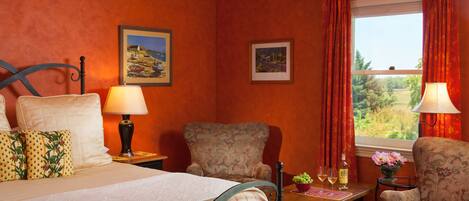 Una habitación de hotel con una cama, dos sillas, una mesa con un florero y una ventana con cortinas.