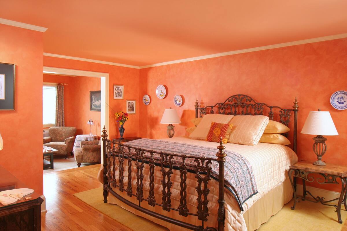 A bedroom with a large bed, two bedside tables, a chair, and a small table with a lamp.