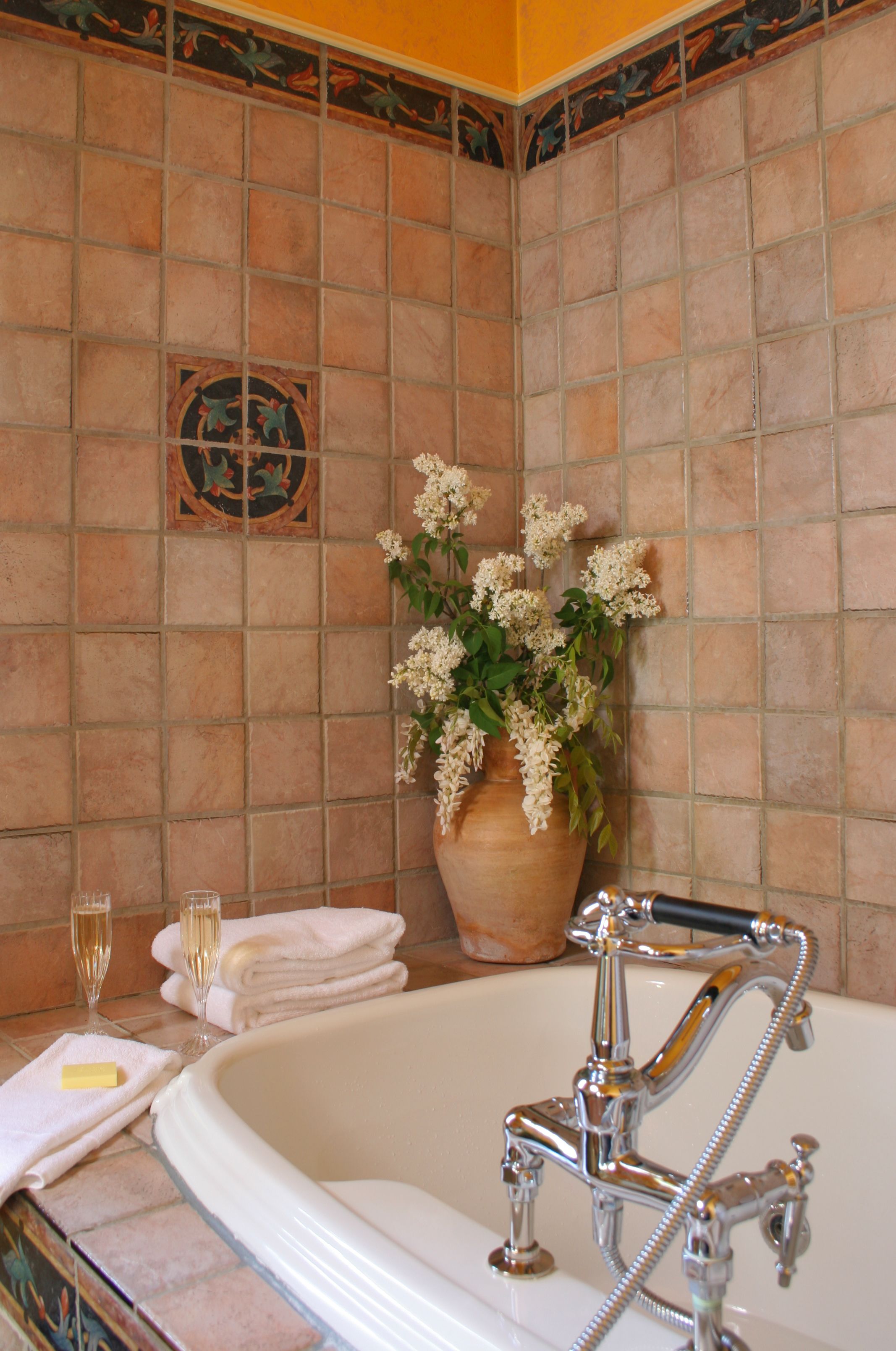 Une salle de bain avec une baignoire, une plante en pot et deux flûtes à champagne posées sur une serviette.