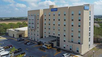 Un hotel a più piani con facciata piatta, un parcheggio con diverse automobili e un cartello che indica che si tratta di un hotel Marriott.