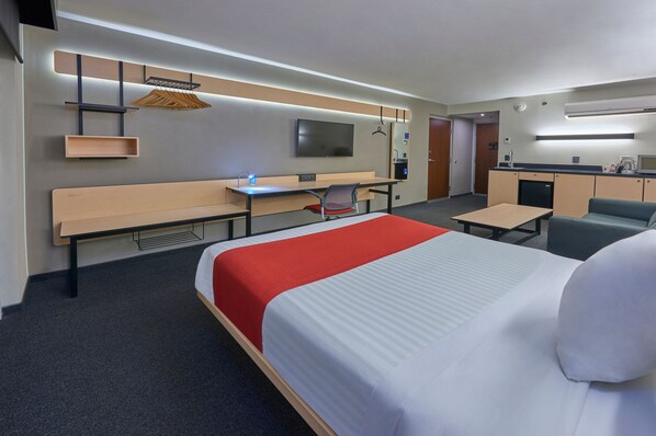 A hotel room with a large bed, a desk, a chair, a TV, a wardrobe, and a kitchenette. - City Express by Marriott Reynosa Aeropuerto (Reynosa)